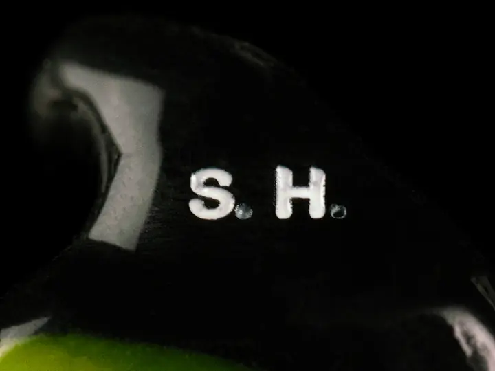 Black custom earplug with the initials S.H. engraved on the faceplate