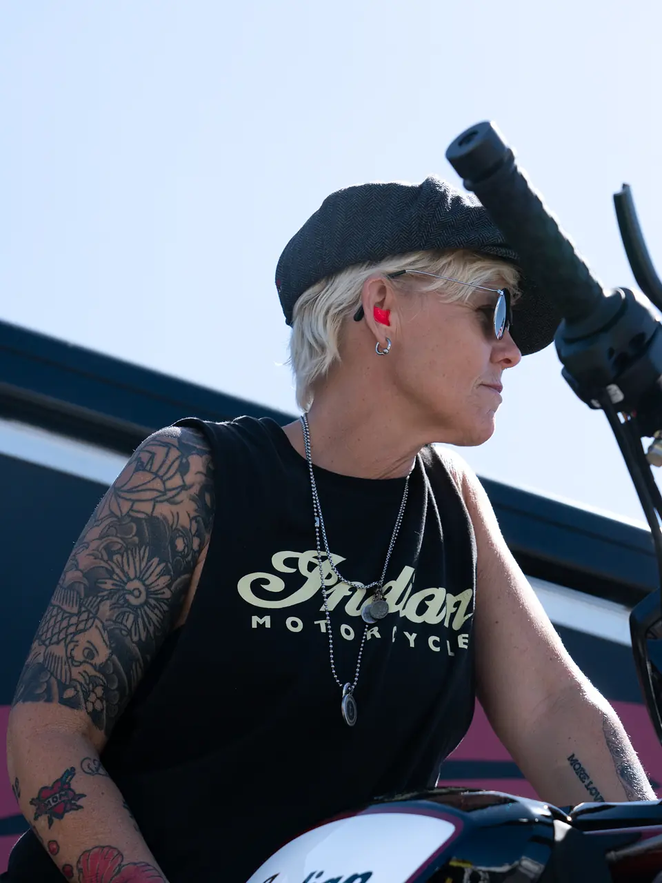 Tattooed rider seated on her motorcycle wearing a pink Big Ear custom earplug