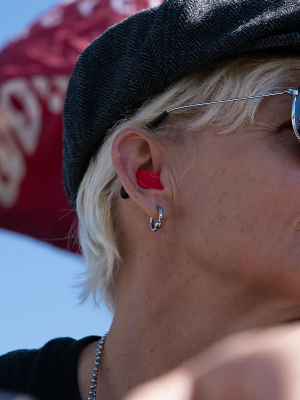 Rider in a flat cap and sunglasses with a red Big Ear custom earplug seated in her ear