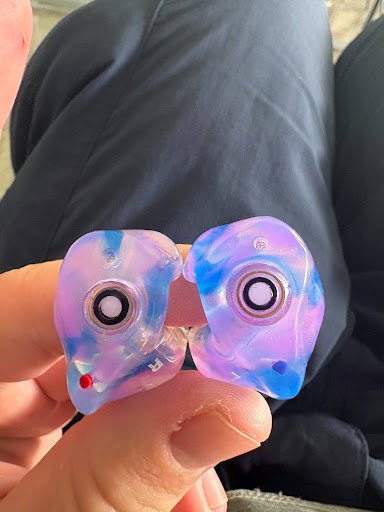 Rider holding blue and purple swirl custom Big Ear The One filtered earplugs