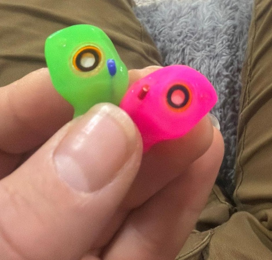 Rider holding green and pink custom Big Ear The One filtered motorcycle earplugs