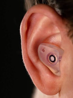 Clear custom Big Ear filtered earplug worn in a rider's ear