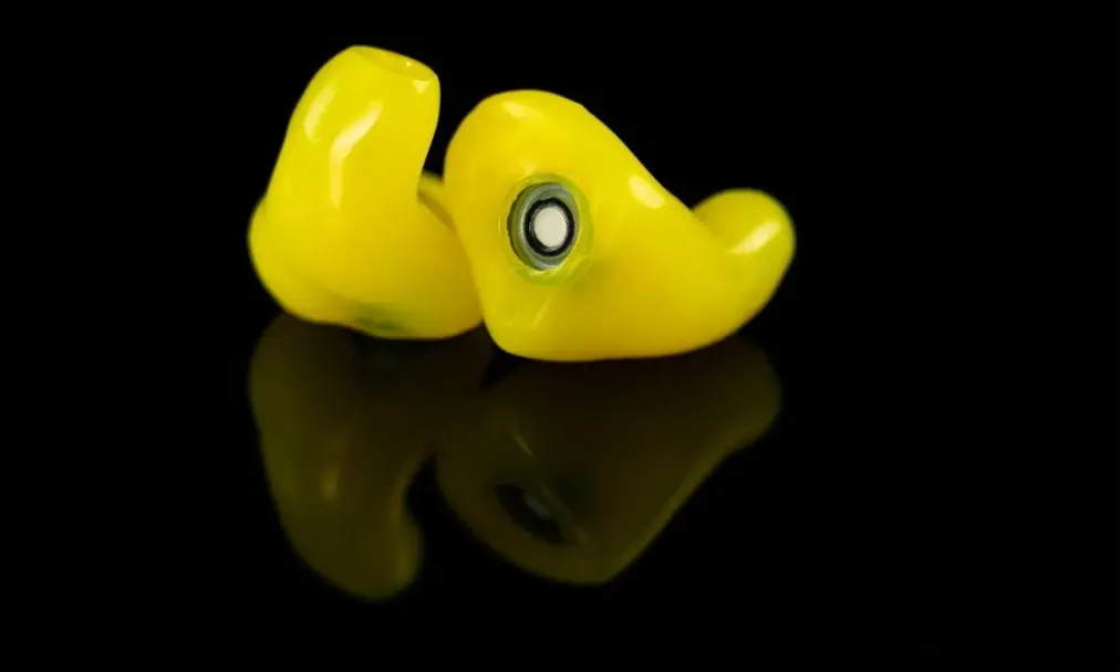 A pair of custom-molded The One earplugs in yellow, showing the filter port