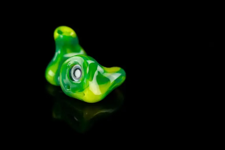 A green custom surfing earplug, built to block water and cold wind