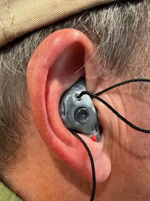 A customer wearing a gray custom The One filtered earplug