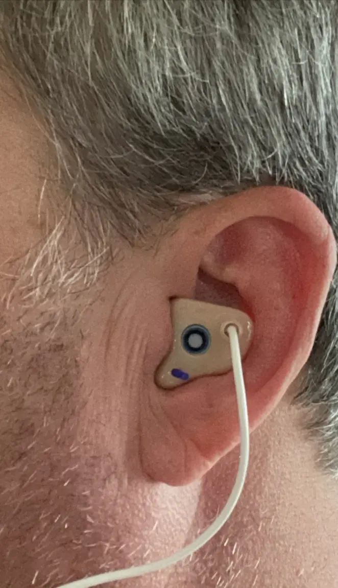A customer wearing a tan custom The One filtered earplug