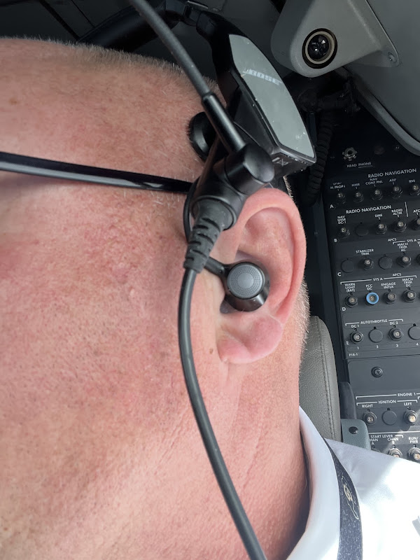 Pilot wearing a Bose ProFlight with a custom Big Ear adapter in the cockpit beside the radio nav panel